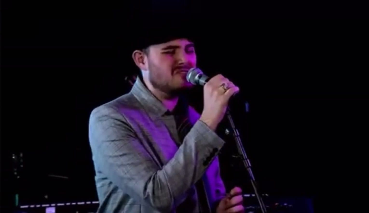 Bradley singing into a microphone on stage