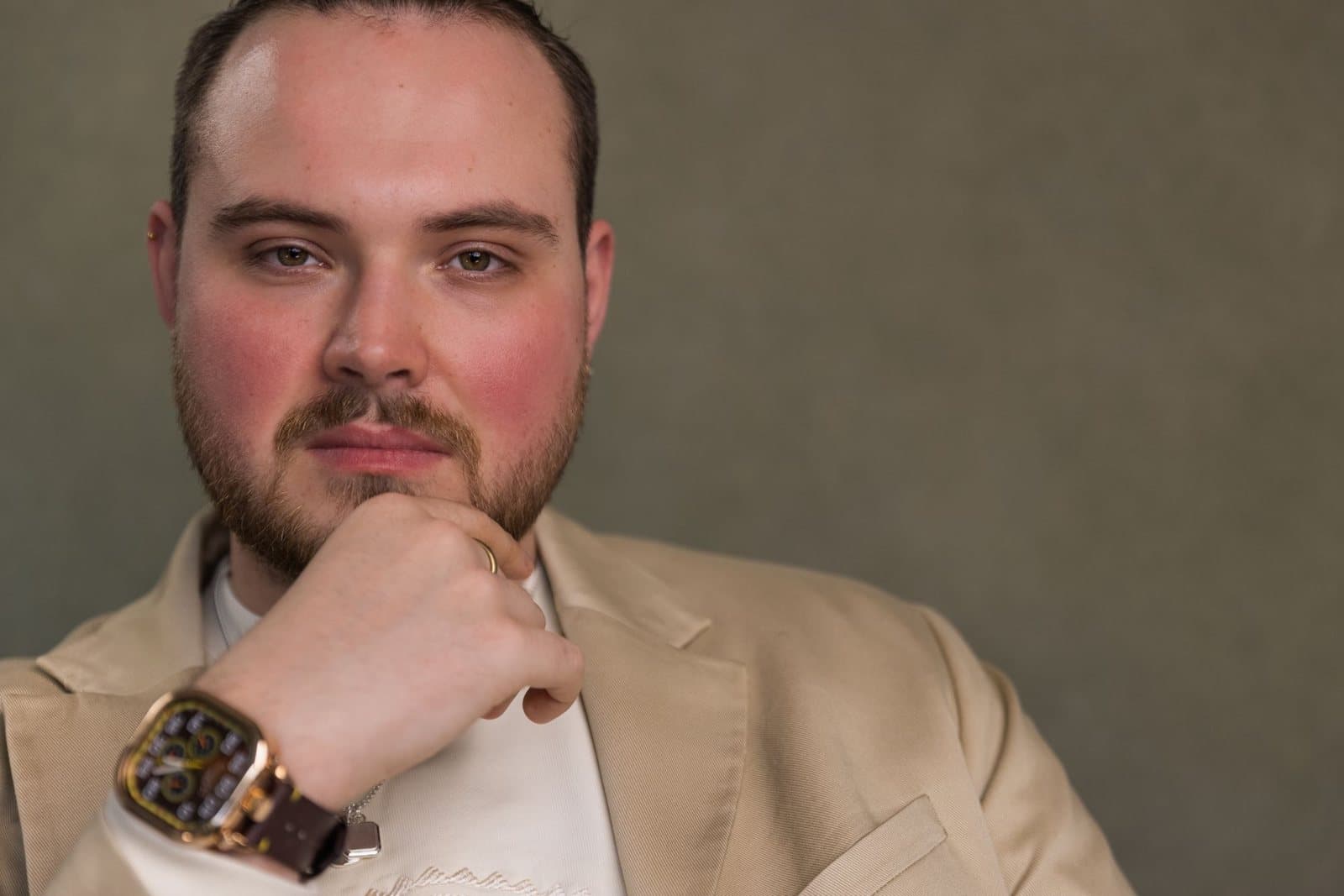 Bradley Barton-Young, chin resting on his hand, in a cream jacket